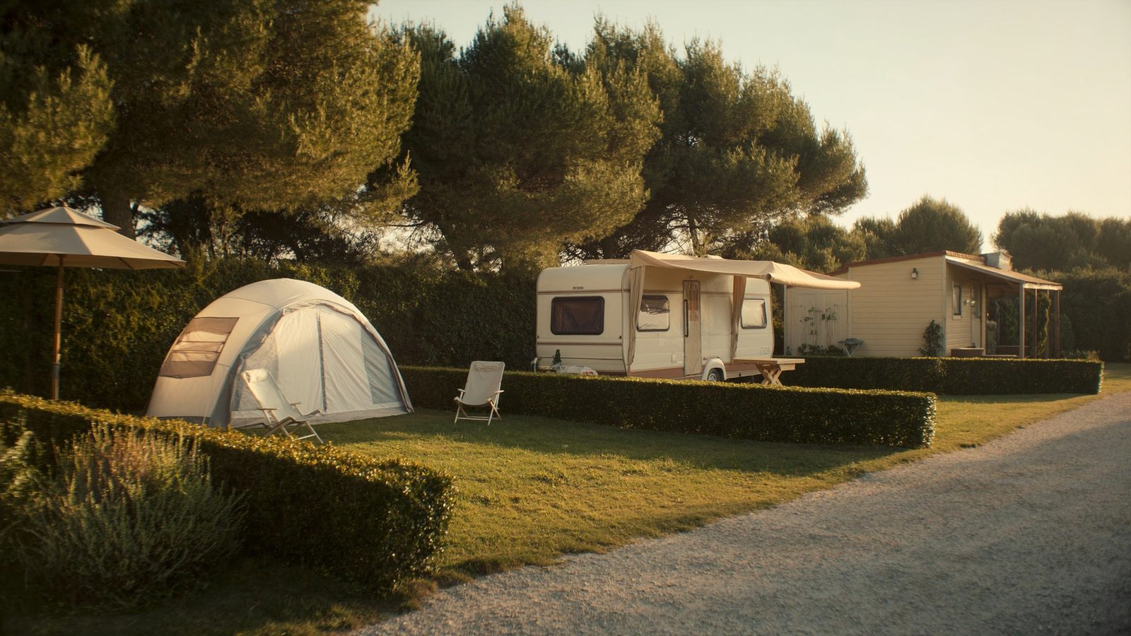 Piazzole di tipo diverso una accanto all'altra: tenda, caravan con veranda e bungalow, separate da siepi